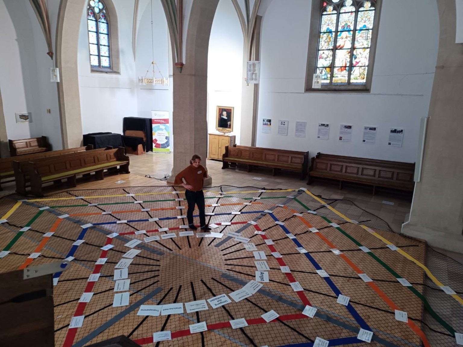 Die im Raum ausgelegte Inner-Horizons-Karte: farbige Achsen und Begriffskarten auf dem Boden einer Kirche, eine Person steht im Zentrum der Karte.